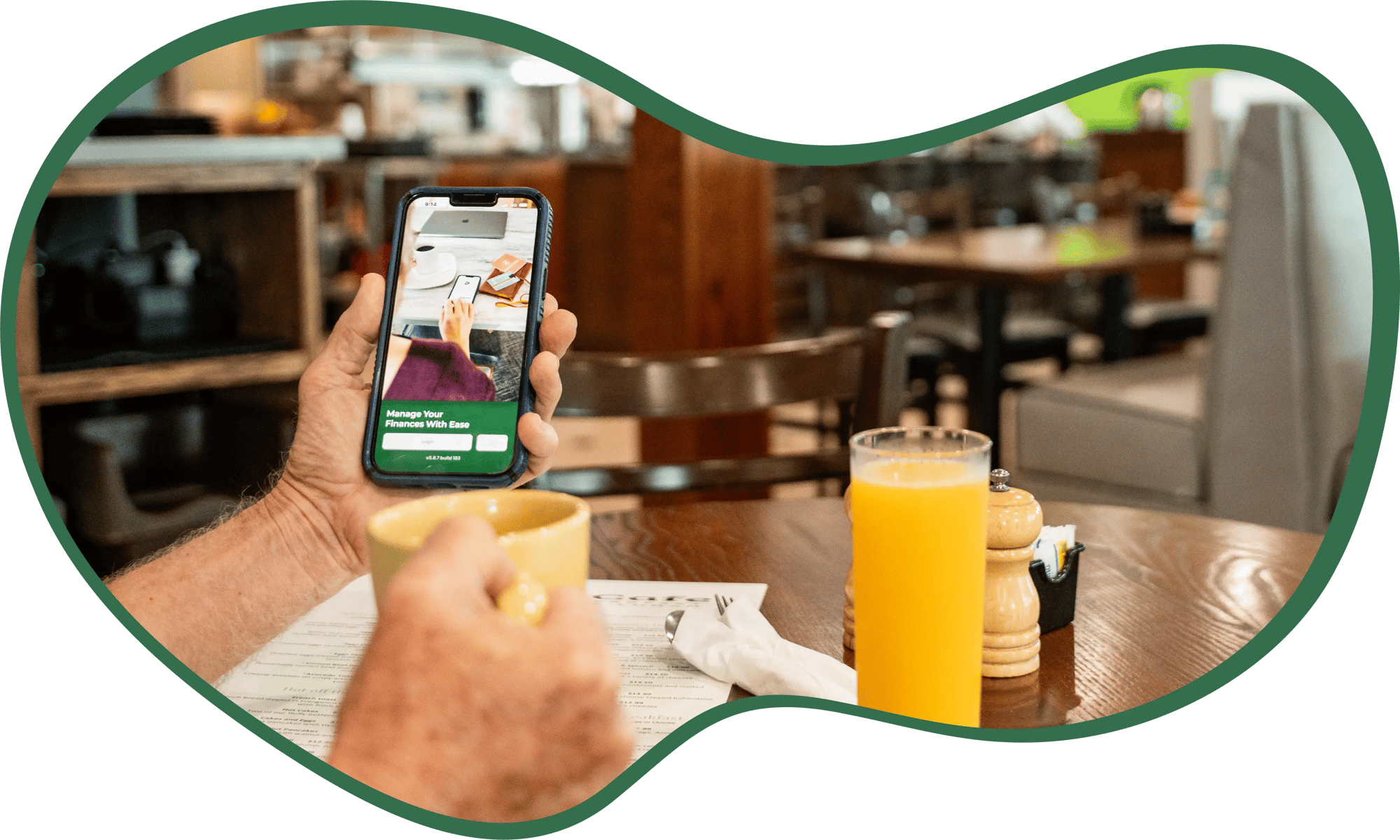 Hands of a man holding mobile phone open to Legacy Bank app in left hand and mug in right hand.