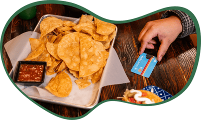 Chips and salsa on a table next to hand with Legacy Bank card
