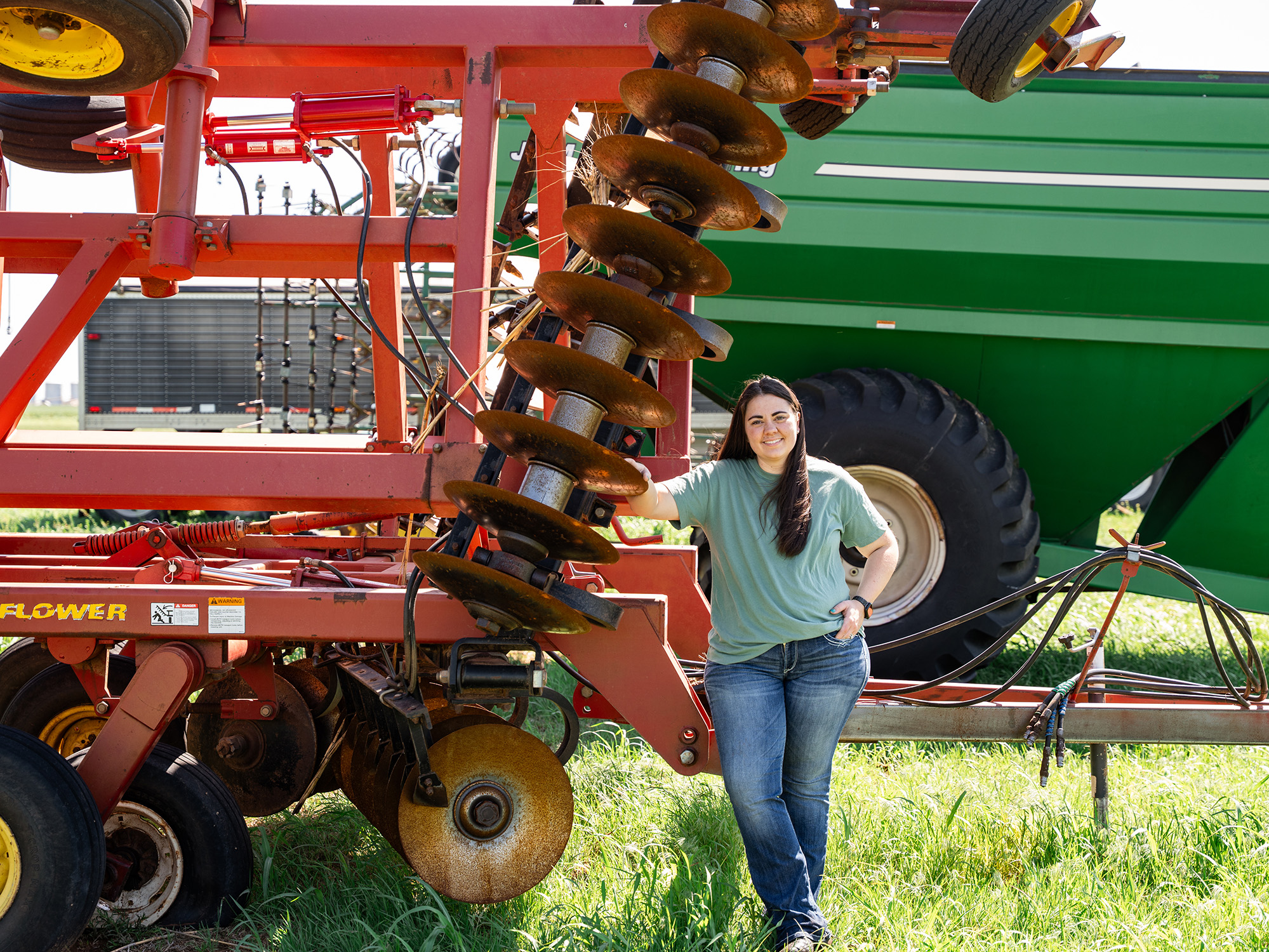 Woman smiling while posing with two tractors.