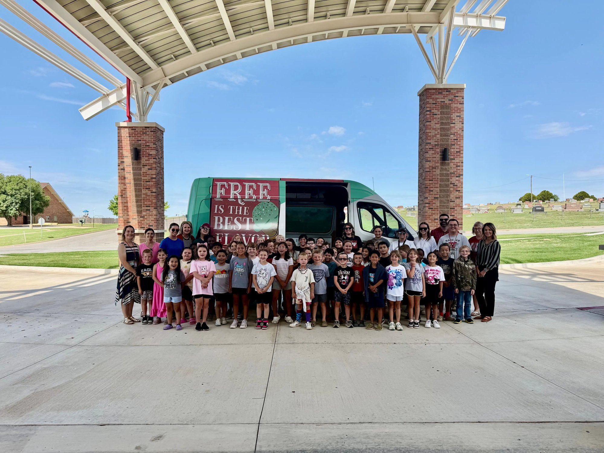Ice Cream truck at an elementary school with children in front. 